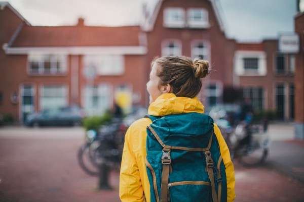 female college student with yellow jacket and blue bookbag walking to school