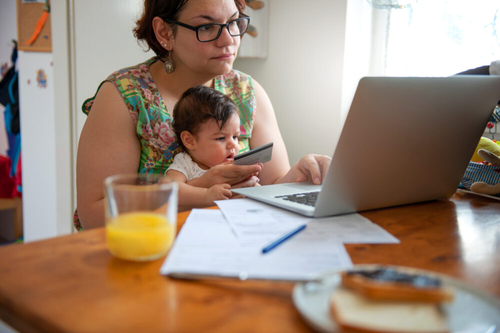 Mother paying bills online, holding her baby in the lap