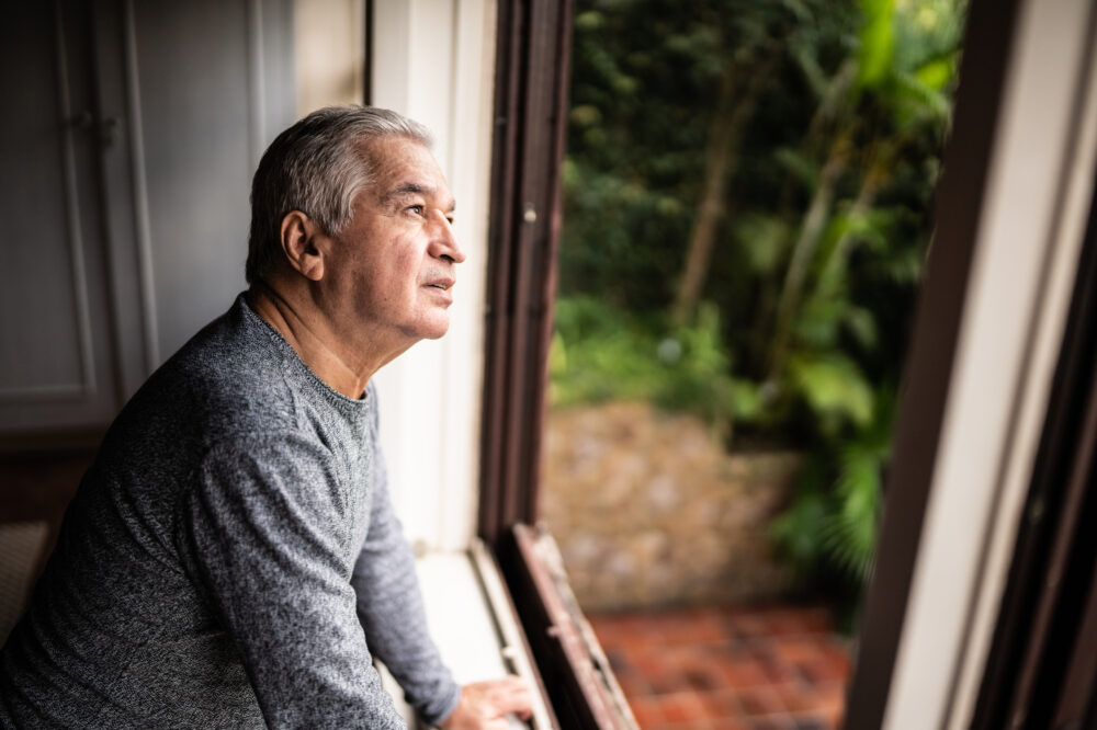 Senior man contemplating looking through the window