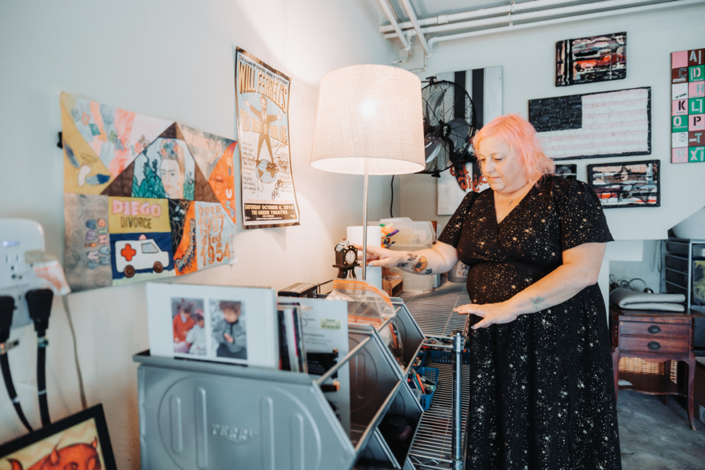 Amanda in home office adjusting a table top clock with lots of artwork on the walls