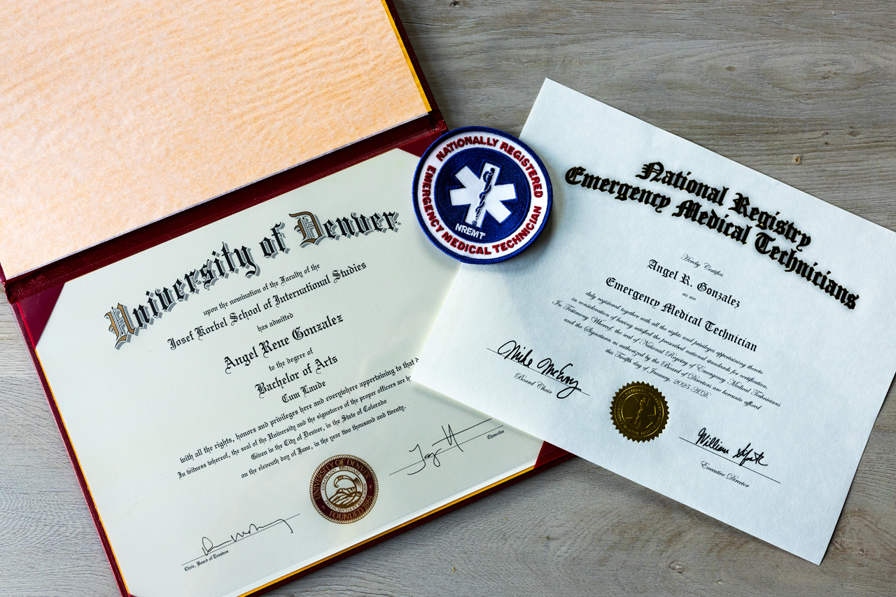Angel's diploma from the University of Denver and their EMT certificate and badge