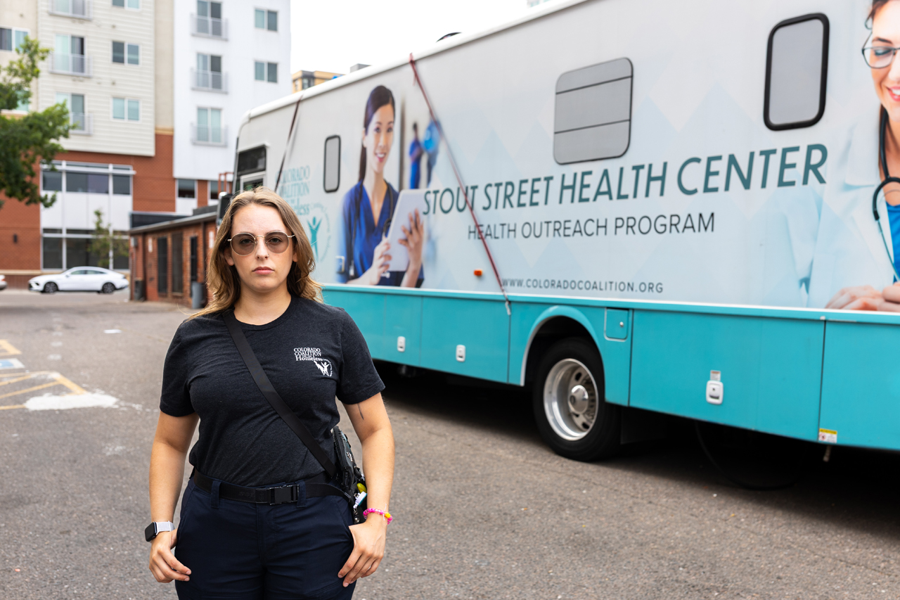 Angel stands in front of the mobile Stout Street Health Center in their work uniform