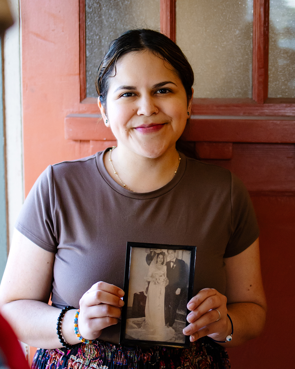 Rebecca holds a framed photo of her parents on their wedding day for the camera to see
