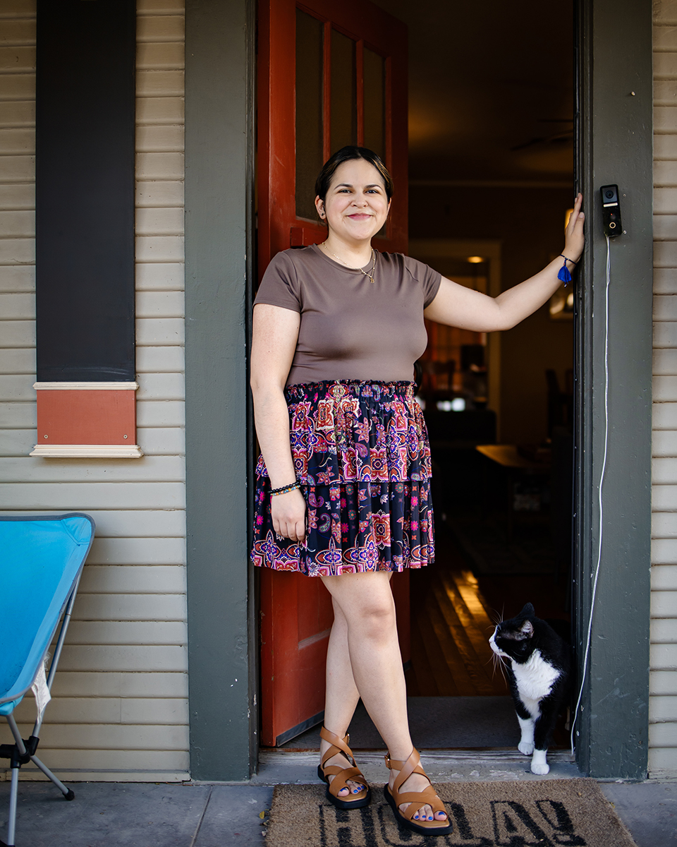 Rebecca and her cat standing in the doorway on her front porch