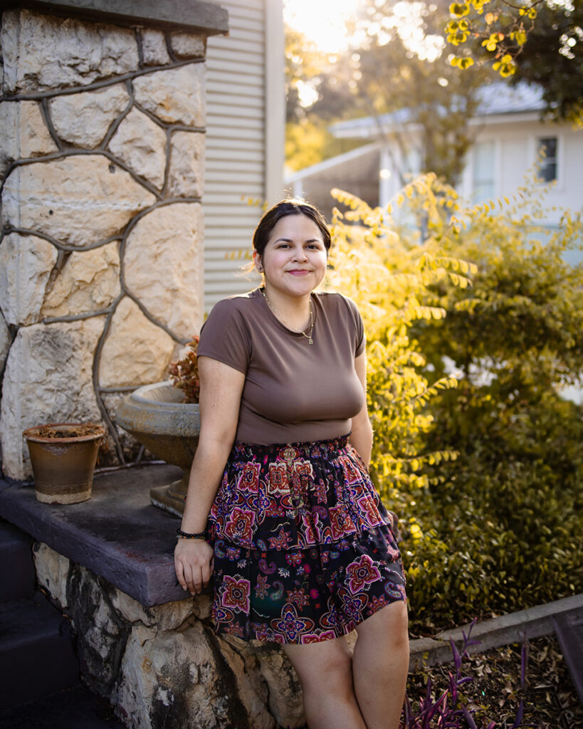 Becky leans on the front stoop of her home and smiles