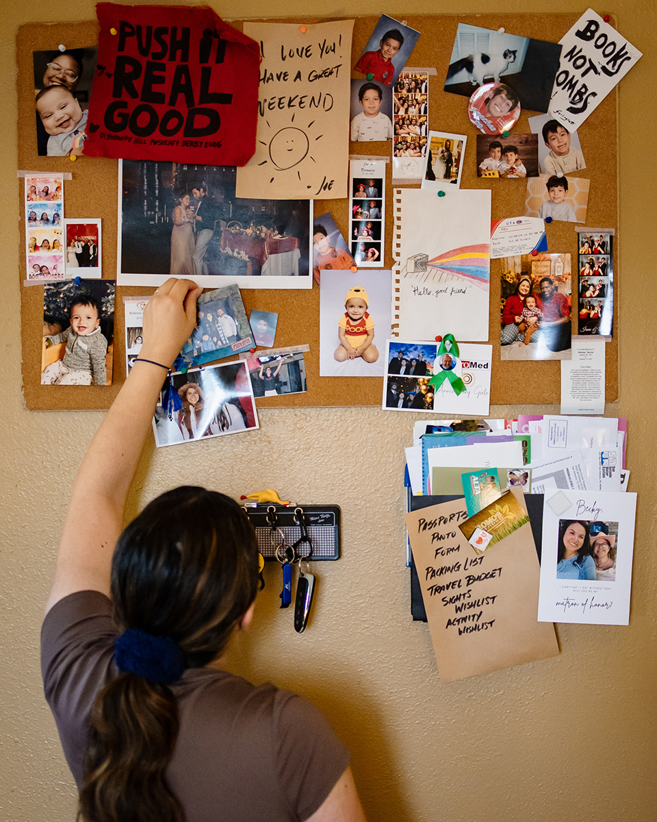 Rebecca adds a photo to the corkboard on her wall which is covered in memories