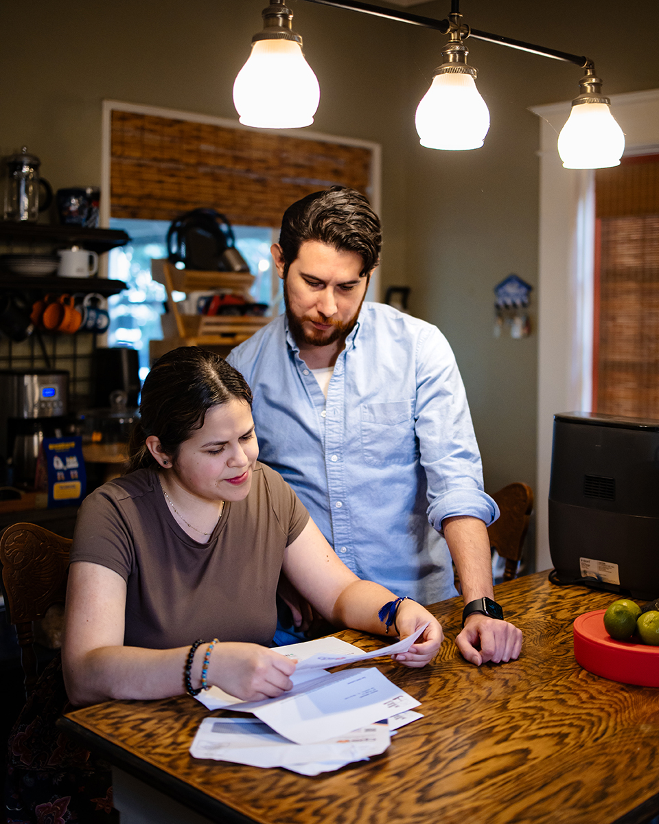 Rebecca and her husband go through bills at the kitchen table