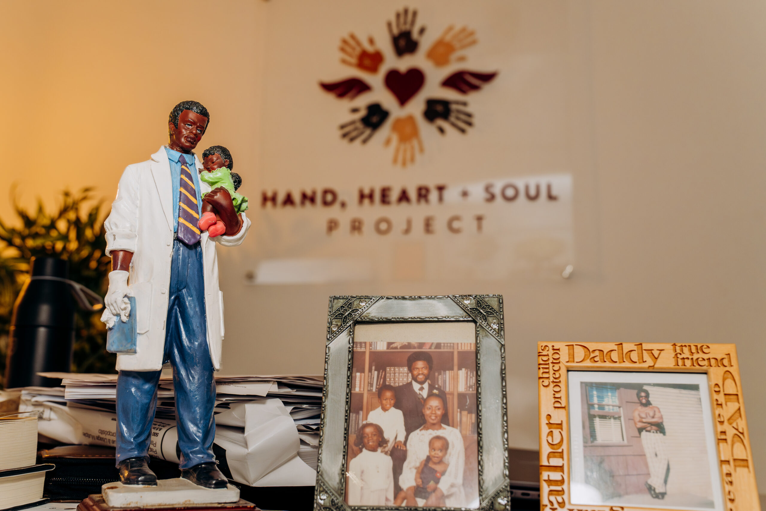 A desktop statue of a man holding a baby and family photos at Wande's office