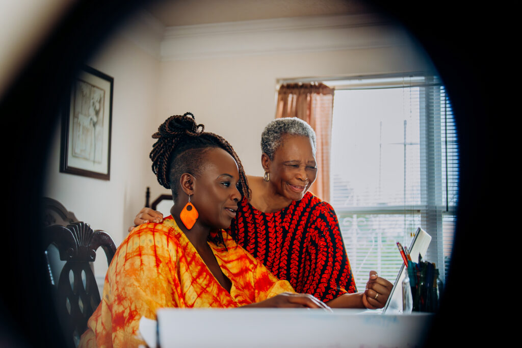 Ori's mother smiles over Ori's shoulder as Ori works from home