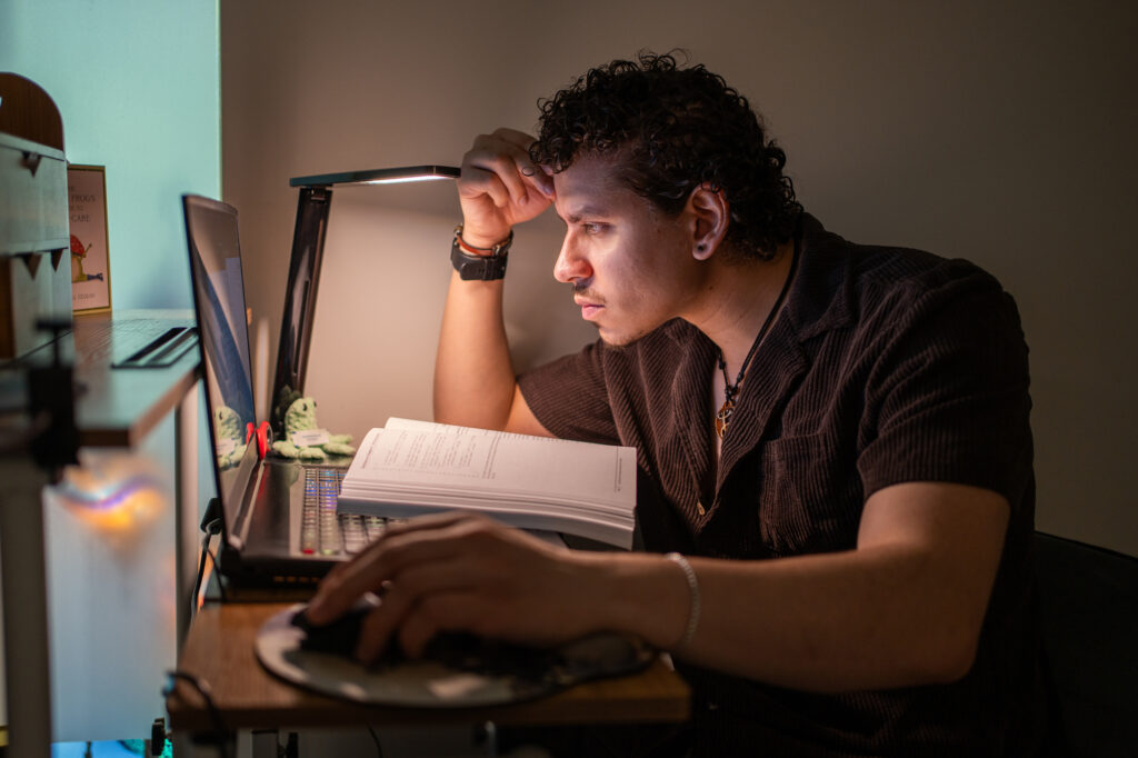 Yousef studies in his home office with a laptop and a textbook