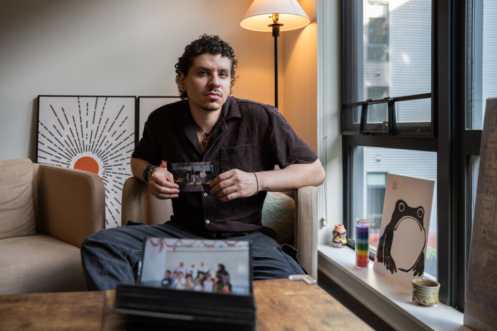 Yousef sits in his living room holding a family photo