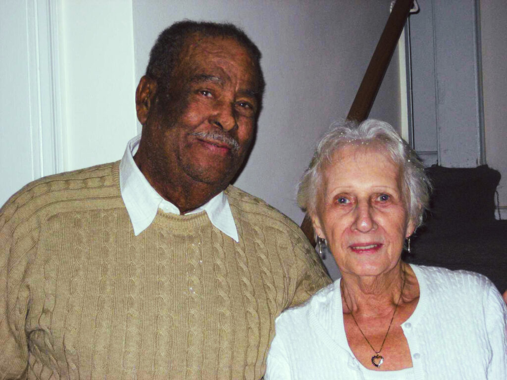 Now an older couple. Fawziah's grandparents smile at the camera in the home