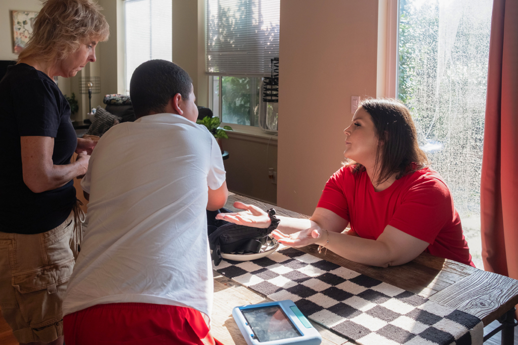 Ashley sits at the dining table talking to her son and mother